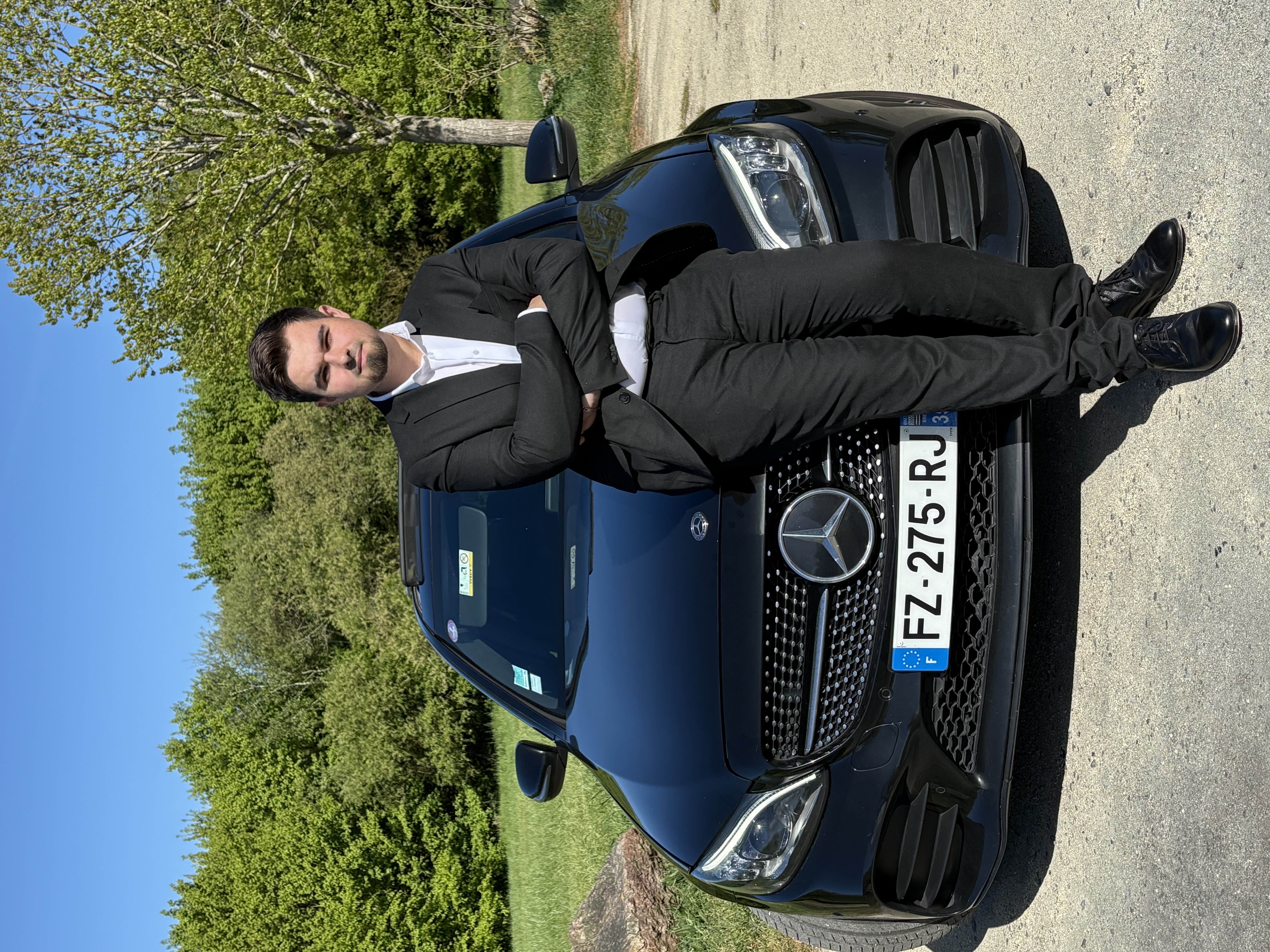 Voiture VTC haut de gamme avec chauffeur privé en costard ouvrant la porte à un client à Rennes.